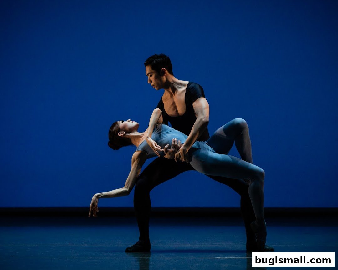 A male and female ballet dancer in a graceful pose against a blue backdrop.