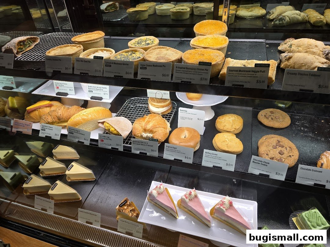 A display case filled with various pastries, pies, sandwiches, and cakes.