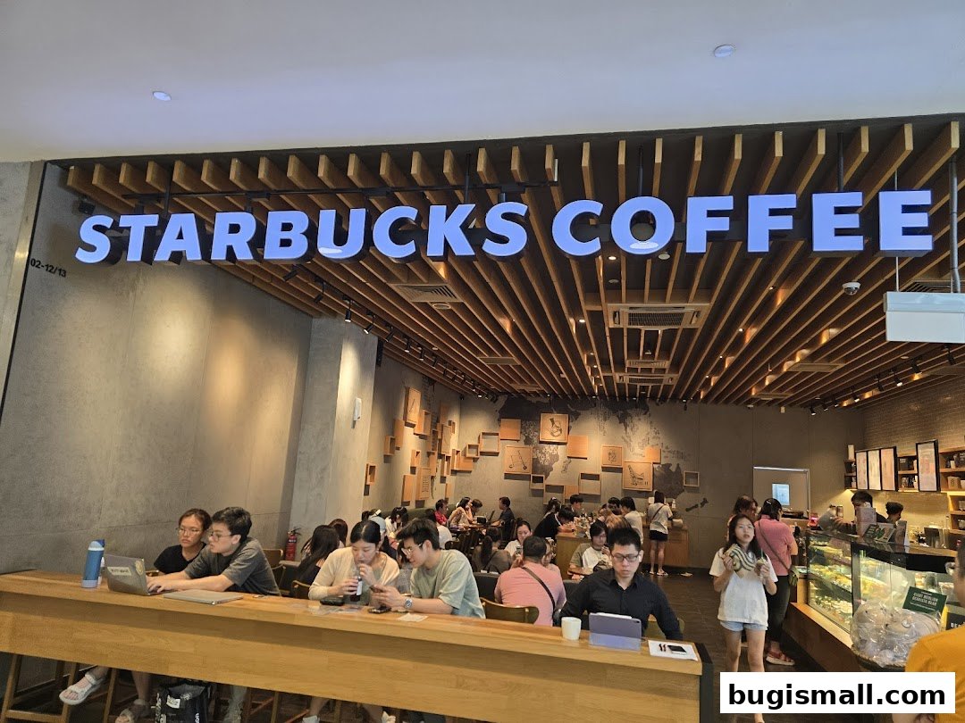 People are seen working and socializing inside a busy Starbucks coffee shop.