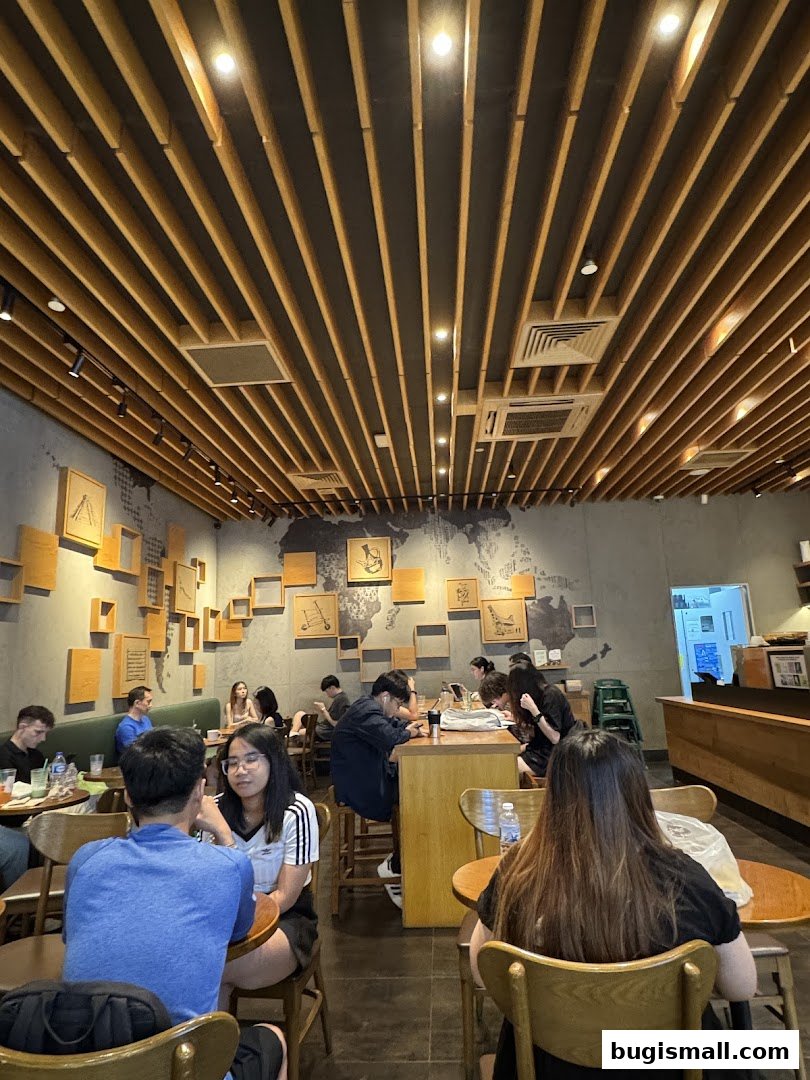 Interior of Starbucks Bugis with customers seated at tables and a unique wooden slatted ceiling.
