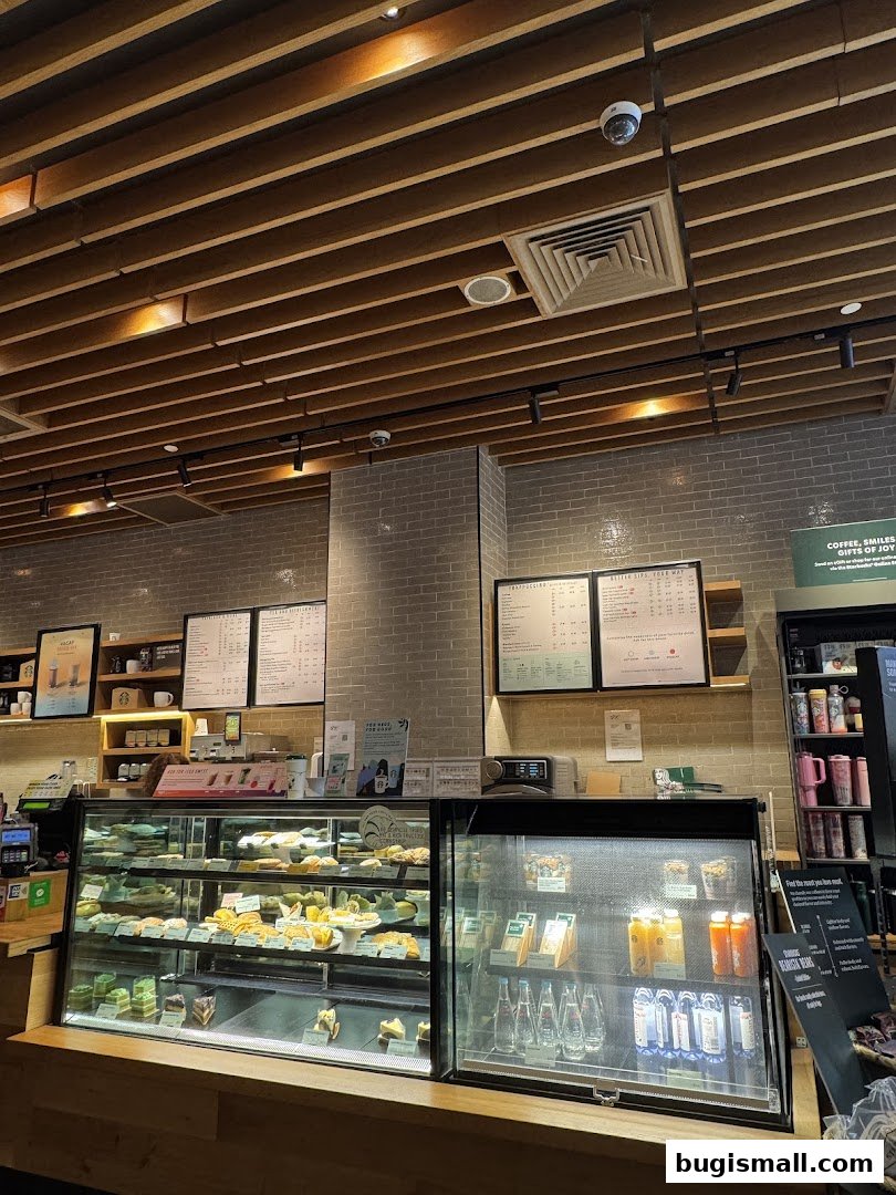 Interior view of a Starbucks cafe showing display cases with pastries and drinks, and menus on the wall.