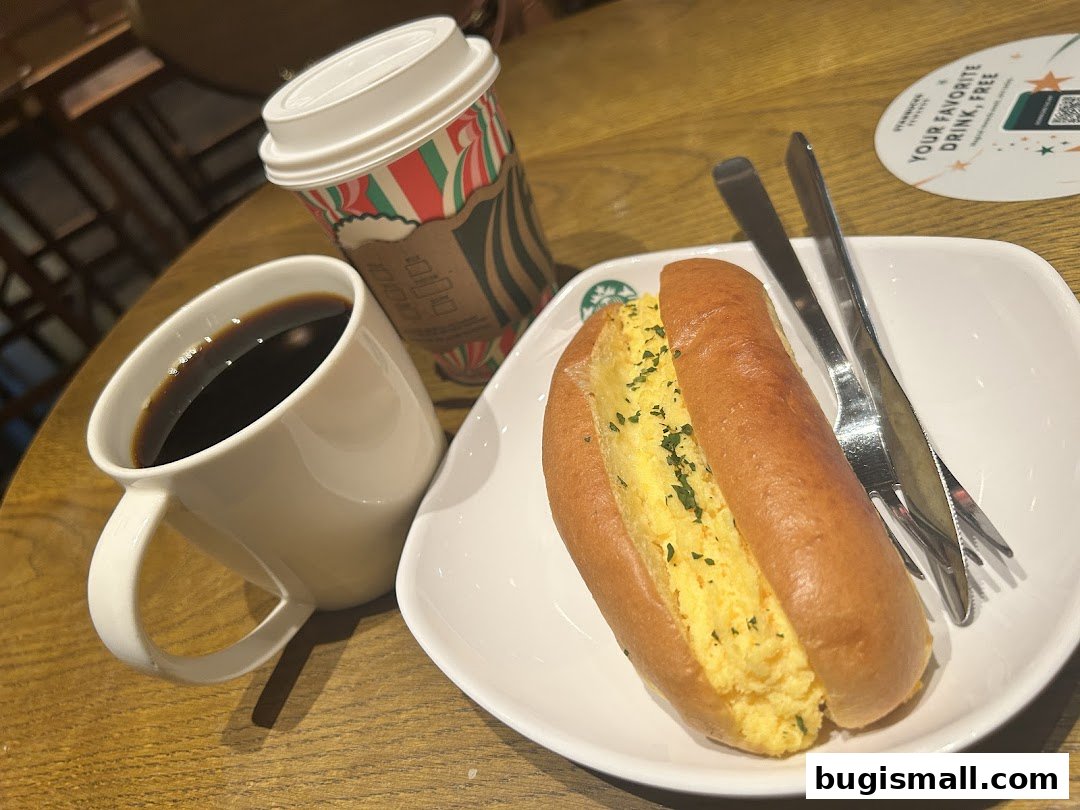 A coffee and a breakfast sandwich are served on a wooden table at Starbucks.