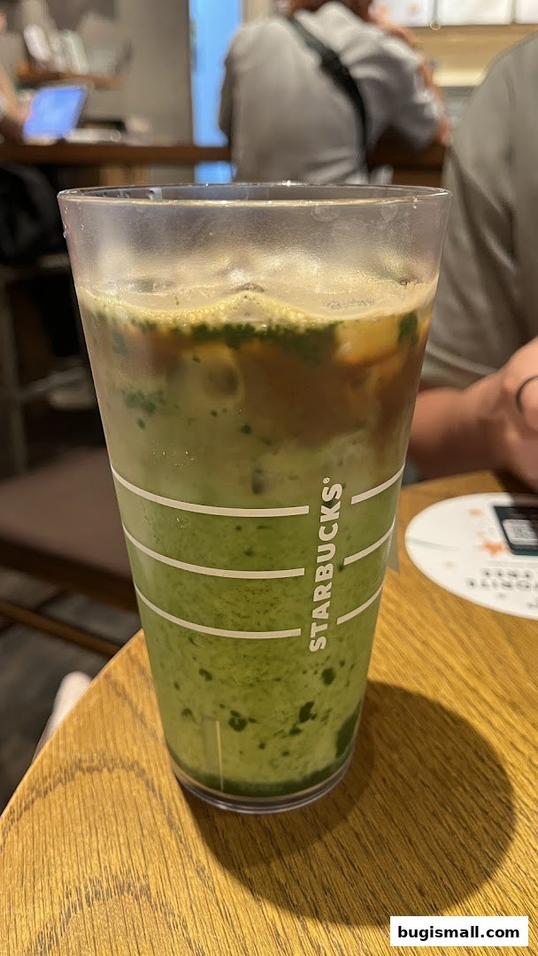 A close-up of a Starbucks iced matcha latte with espresso on a wooden table.