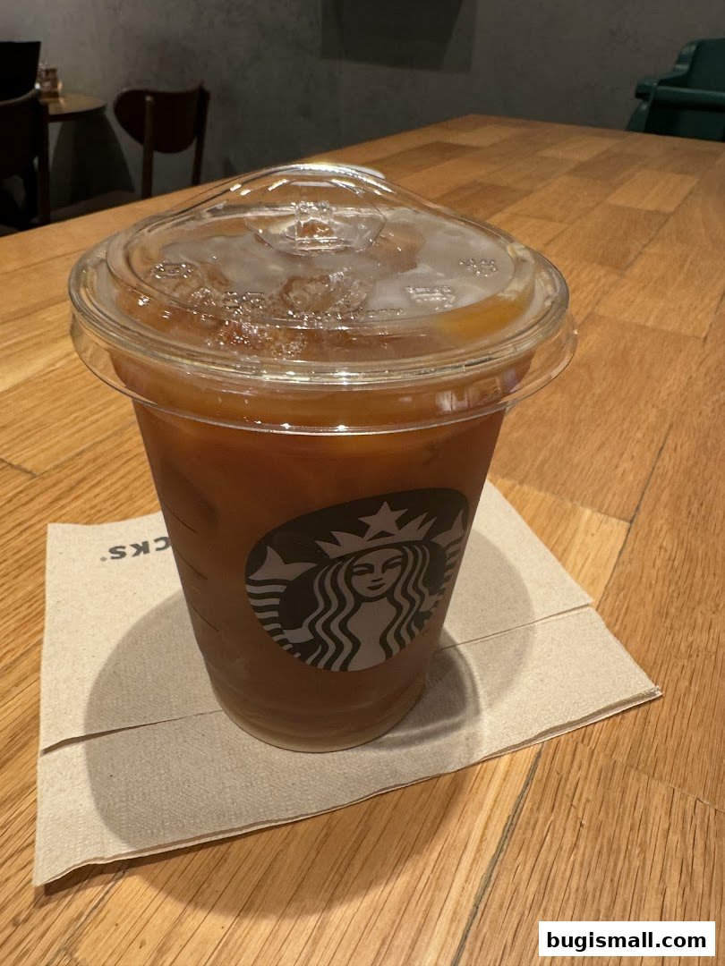 A Starbucks iced coffee drink sits on a napkin on a wooden table.
