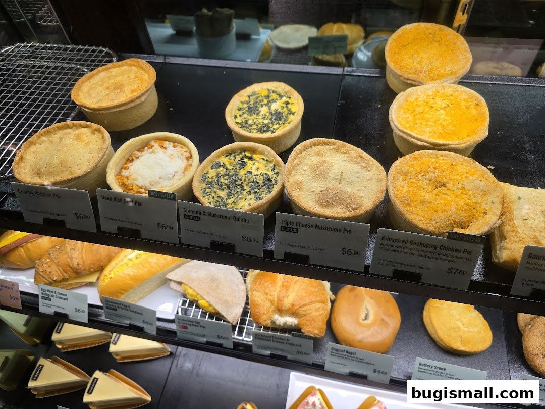 A display case filled with various pies, quiches, sandwiches, bagels, and scones.