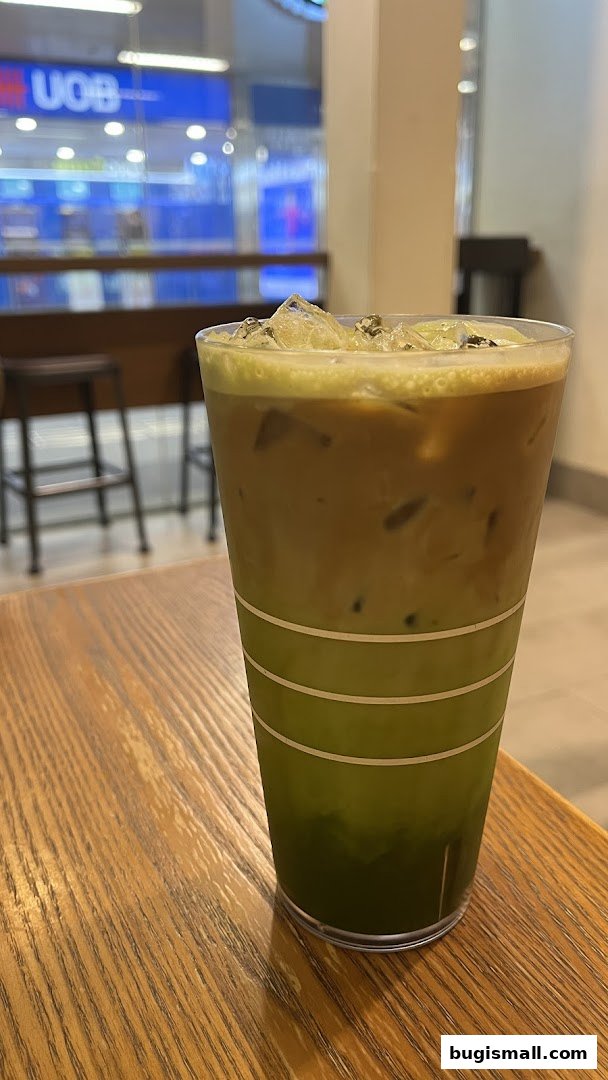 A layered iced coffee drink with matcha and coffee on a wooden table.
