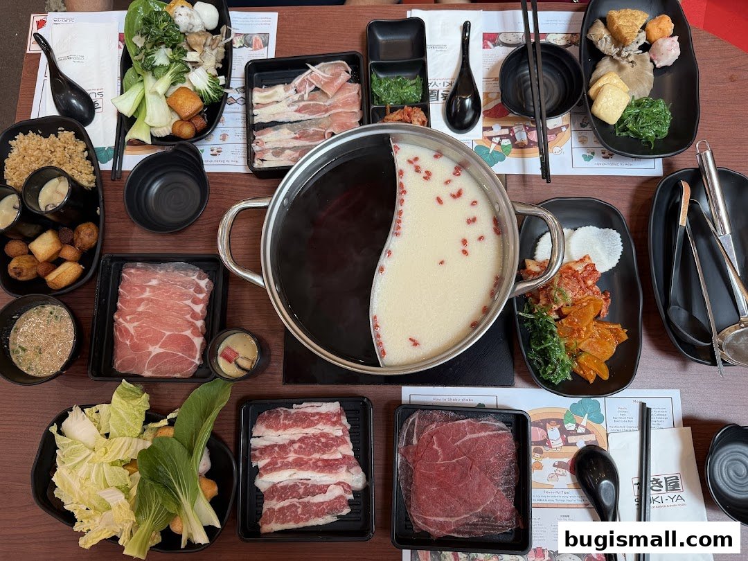A table laden with a variety of shabu-shabu ingredients and a split pot of broth.