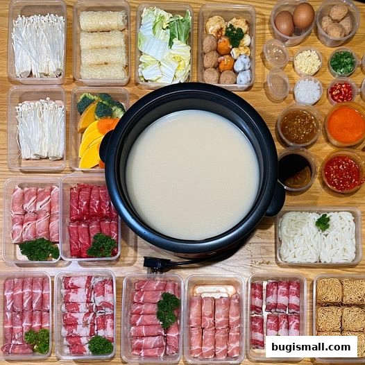 A spread of ingredients for shabu-shabu, including meats, vegetables, noodles, and dipping sauces.