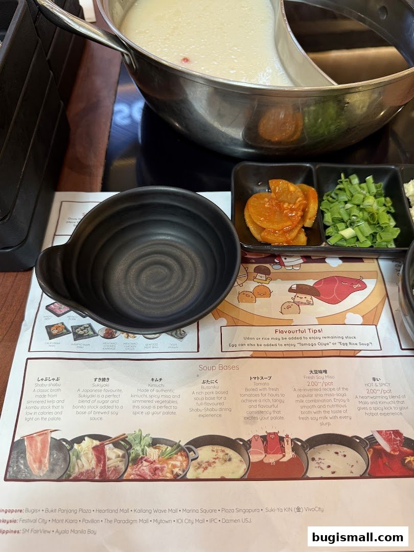 A table setting for a hot pot meal with various soup bases and ingredients.
