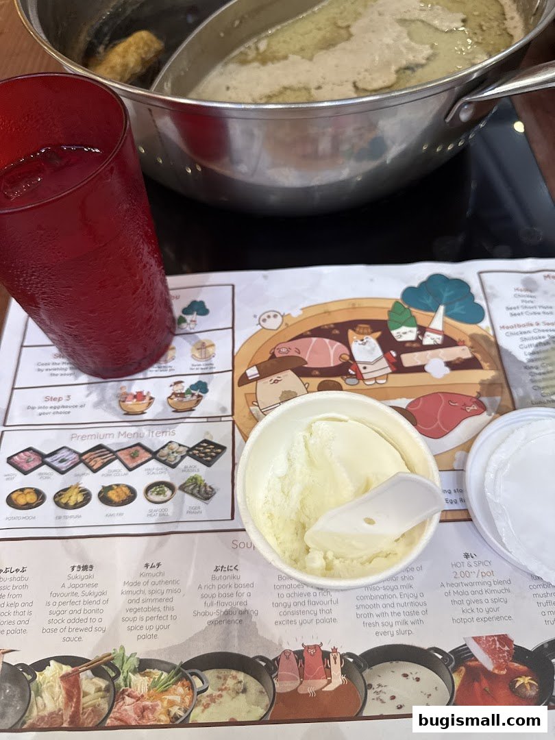 A close-up of a shabu-shabu meal with a red drink and a bowl of ice cream.