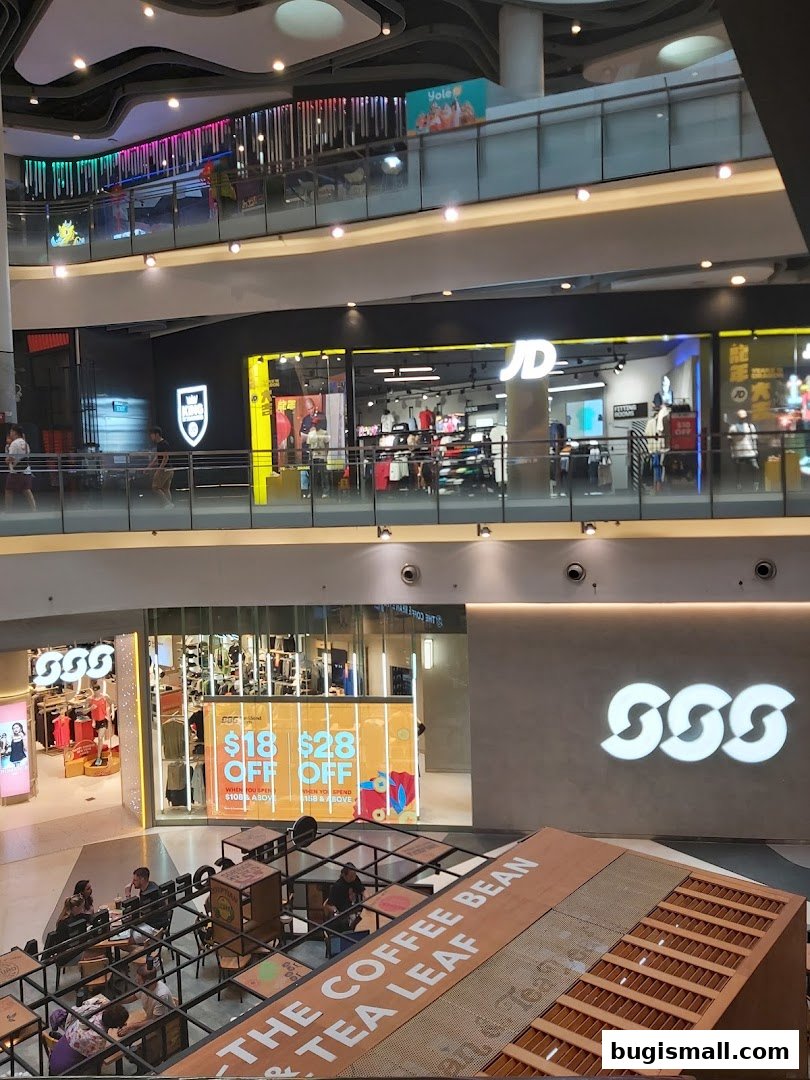 A view of multiple retail stores and a cafe seating area inside a modern shopping mall.
