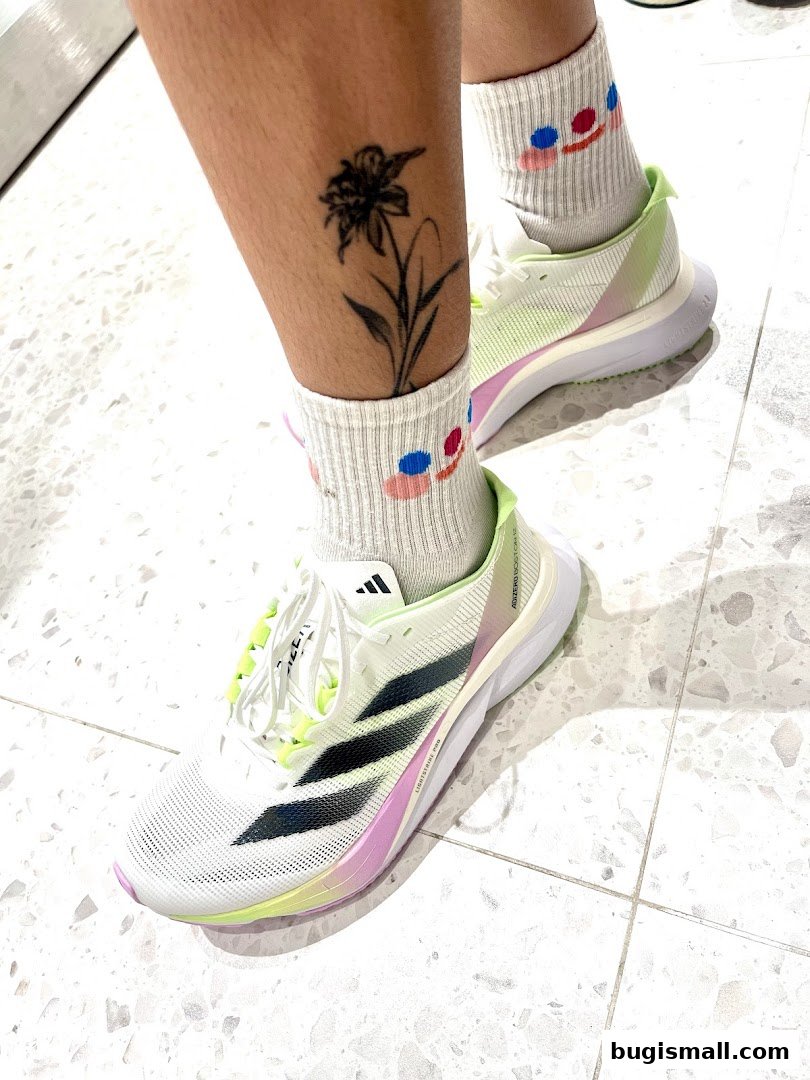 A close-up shot of a person's legs wearing athletic socks and white Adidas running shoes with colorful accents.