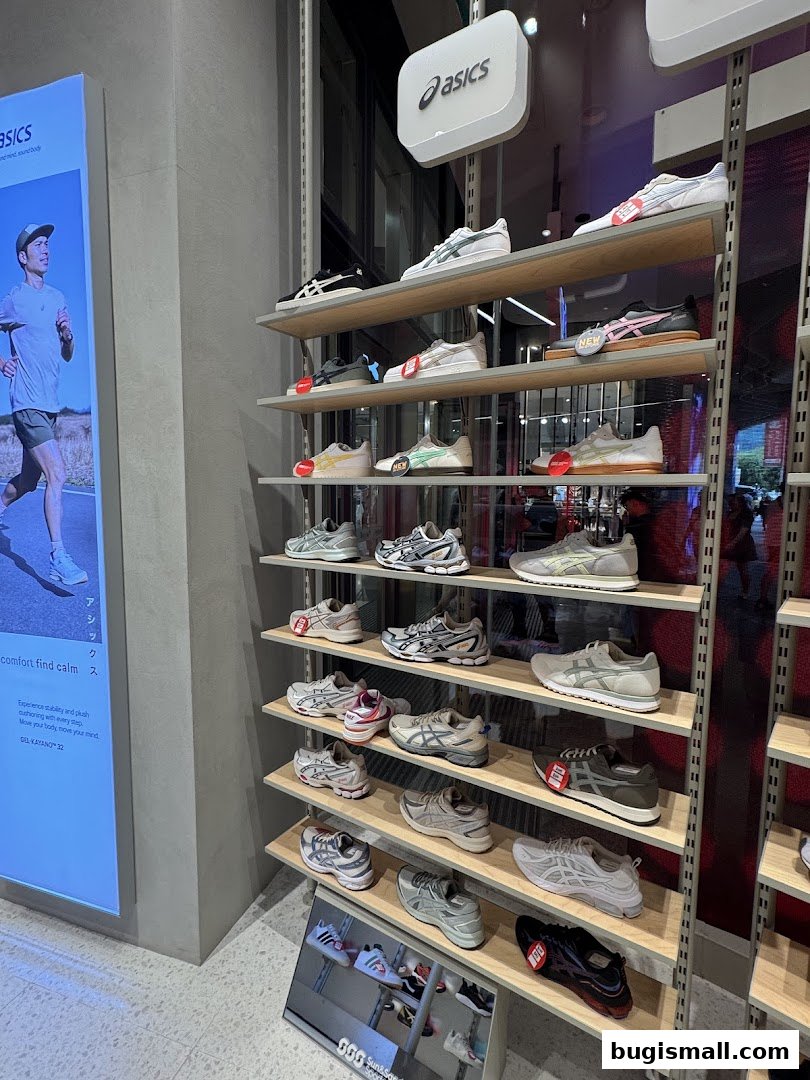 A display of various Asics athletic shoes on shelves inside a store.