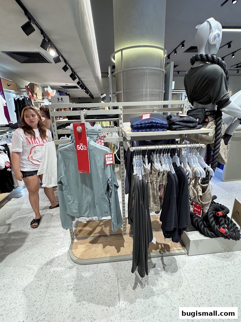Customers browsing sportswear and apparel in a well-lit retail store with mannequins.