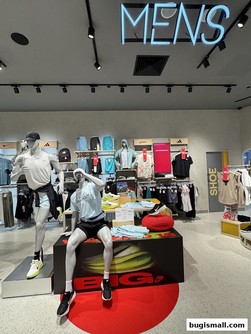 Mannequins display athletic wear and shoes in a brightly lit sports apparel store.