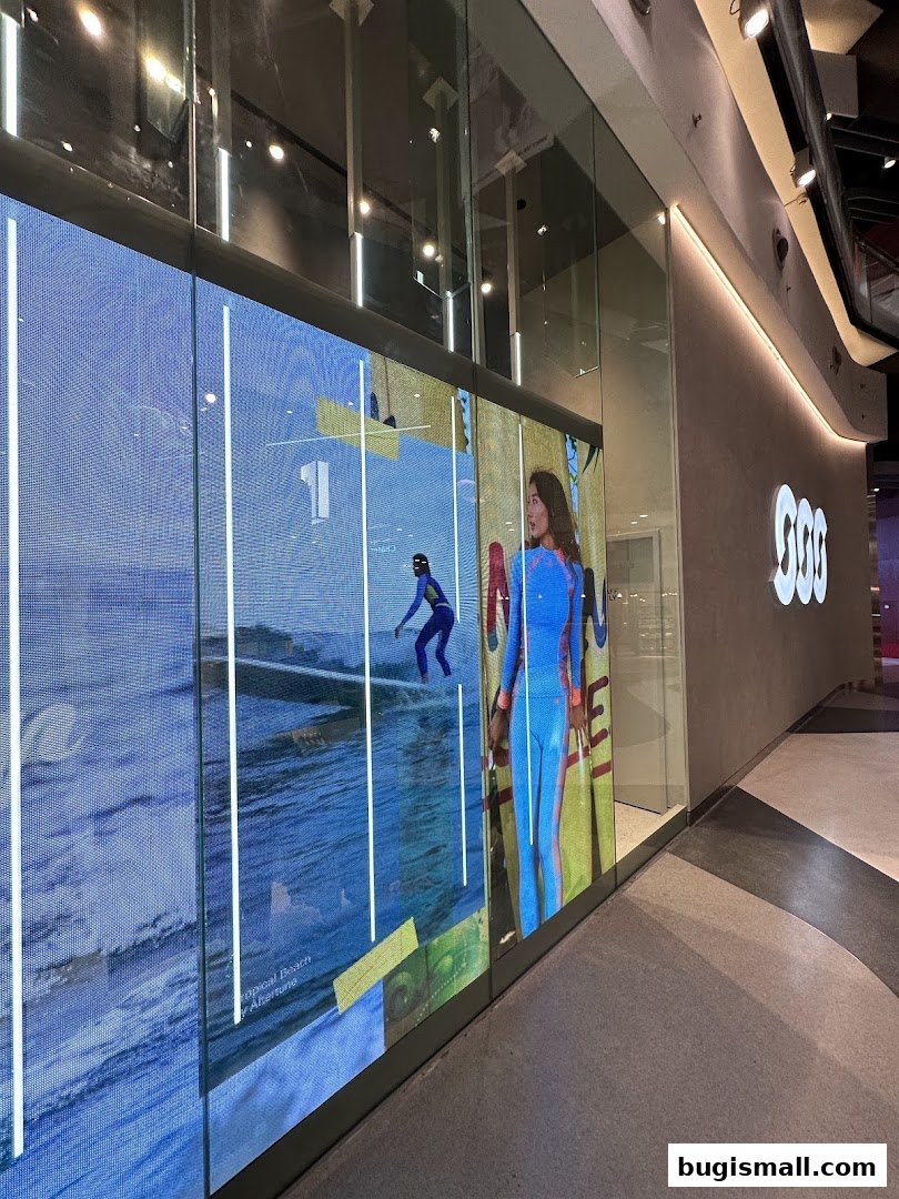 A large digital screen displays surfing imagery and a model in athletic wear.