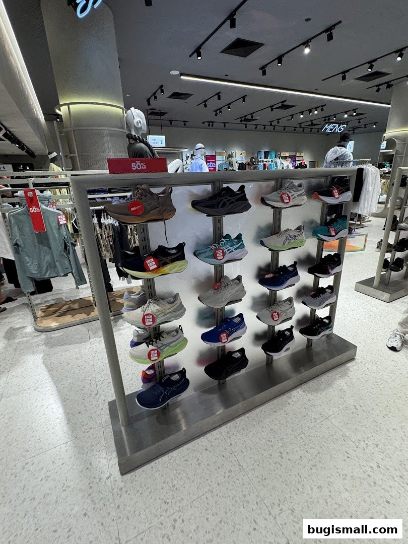 A display of athletic shoes in a retail store, with clothing racks in the background.