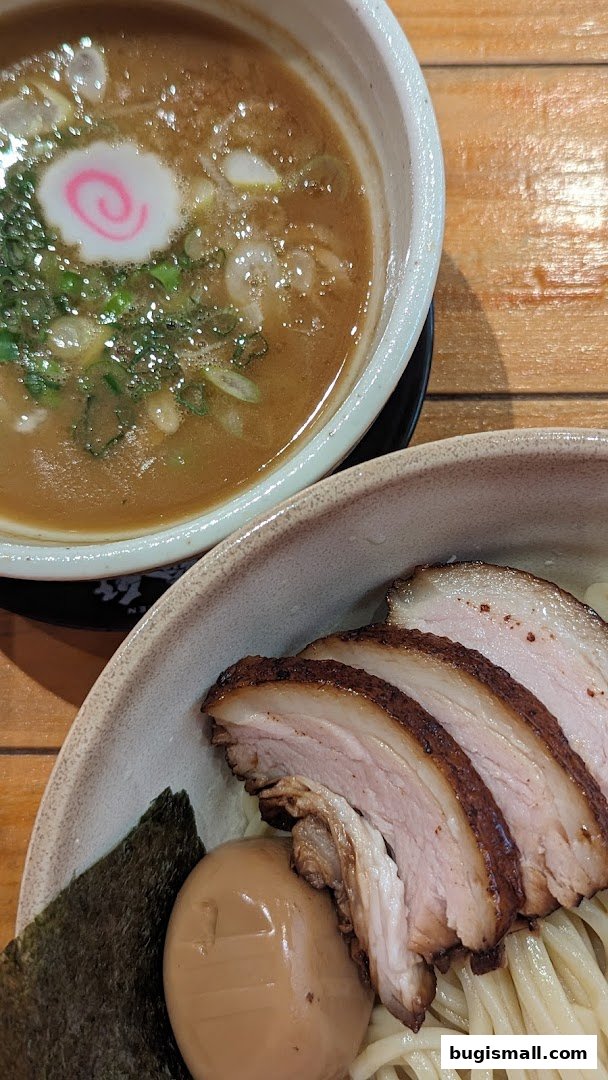 A close-up of a delicious bowl of ramen with tender pork slices, a soft-boiled egg, and nori.