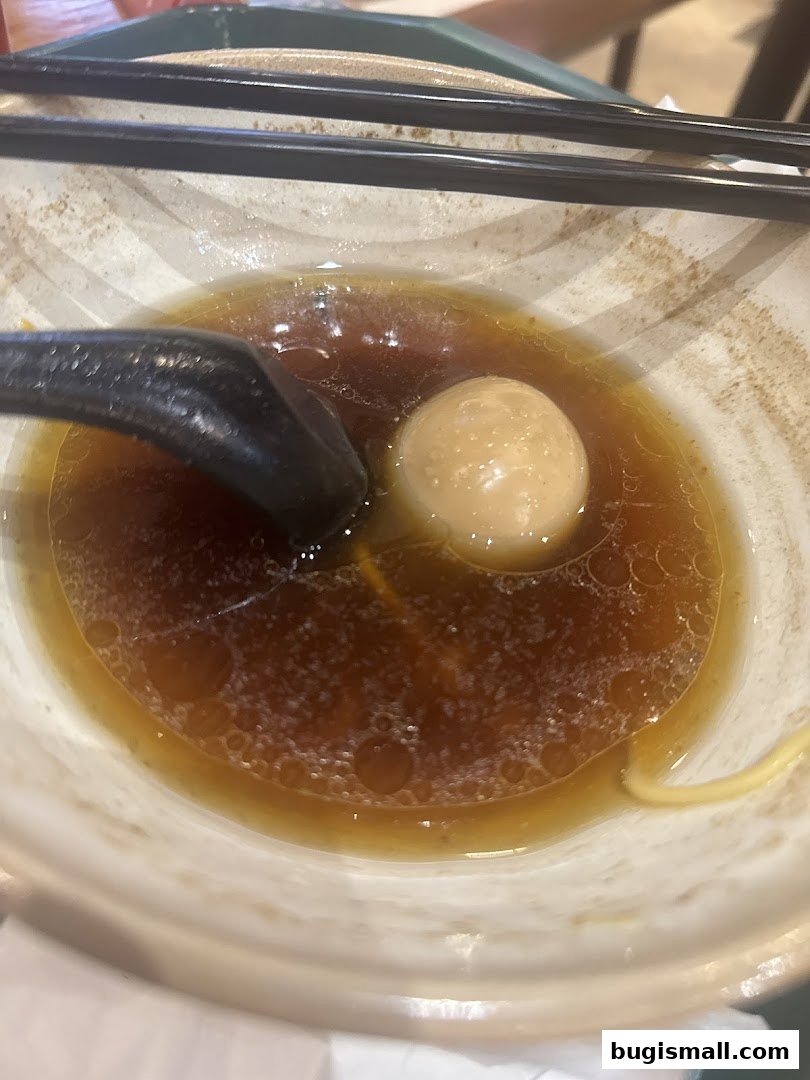 A close-up of a bowl of ramen with broth, noodles, and a soft-boiled egg.
