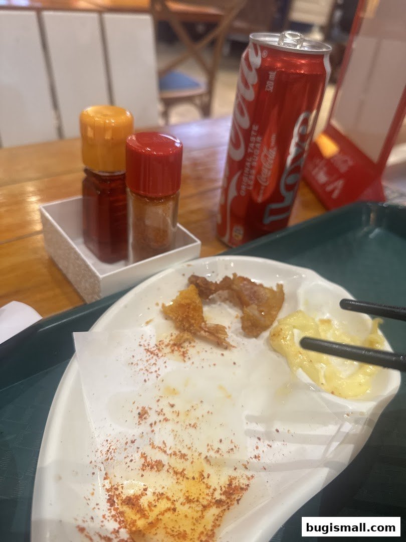 A plate with leftover fried food, spices, and a can of Coca-Cola.