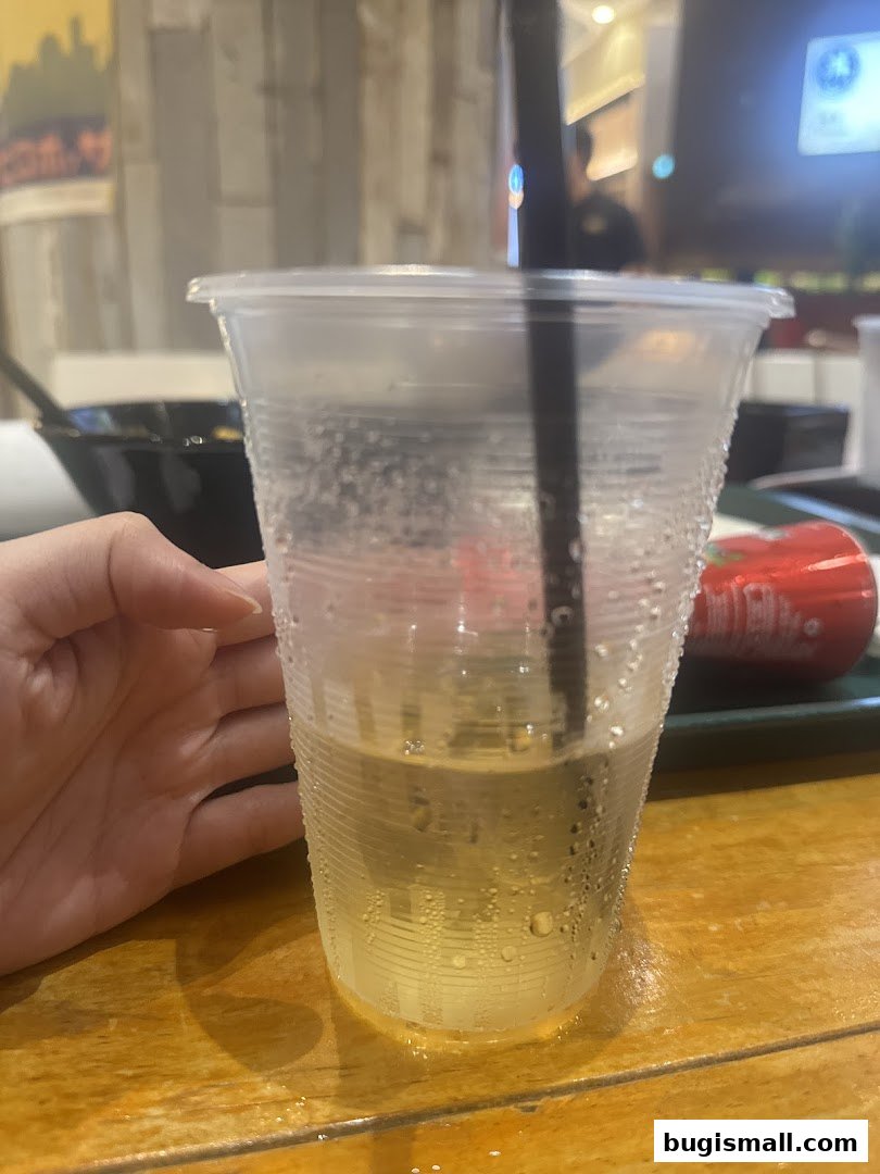 A hand holds a cold, condensation-covered drink with a straw at Taishoken Singapore.