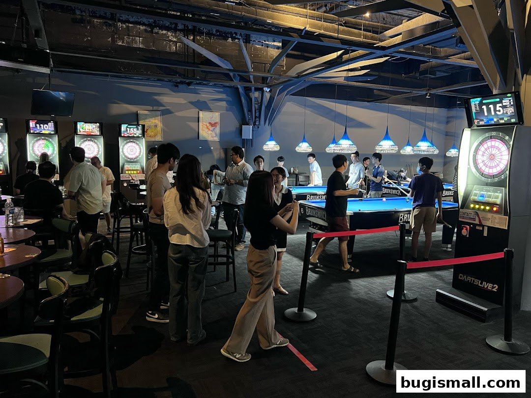 People playing darts and billiards in a dimly lit entertainment venue.