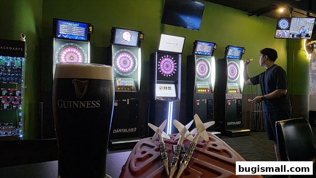 A man plays darts at a bar with a Guinness beer and darts in the foreground.