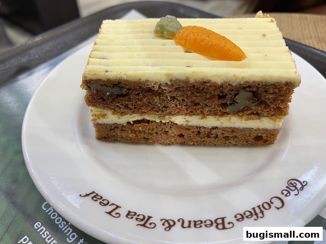 A slice of delicious carrot cake with cream cheese frosting on a white plate.