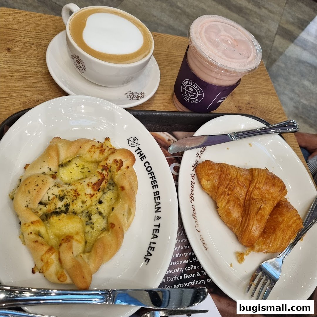 A coffee, a pink drink, a savory pastry, and croissants served on plates.