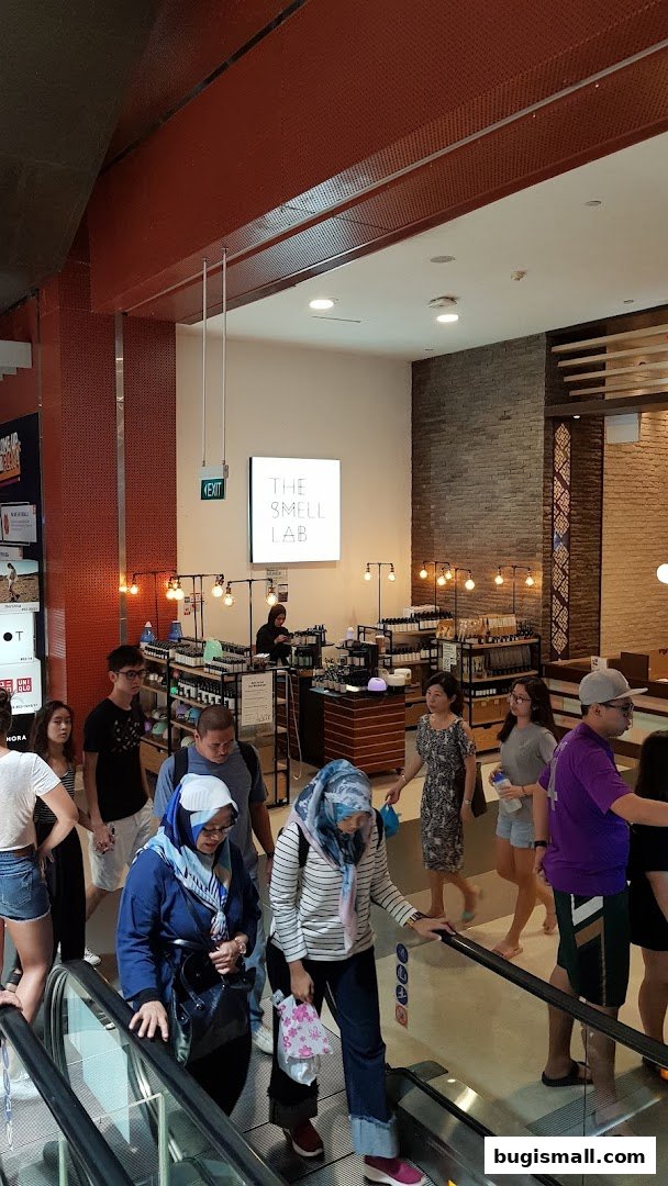 People on an escalator in front of a shop called The Smell Lab.