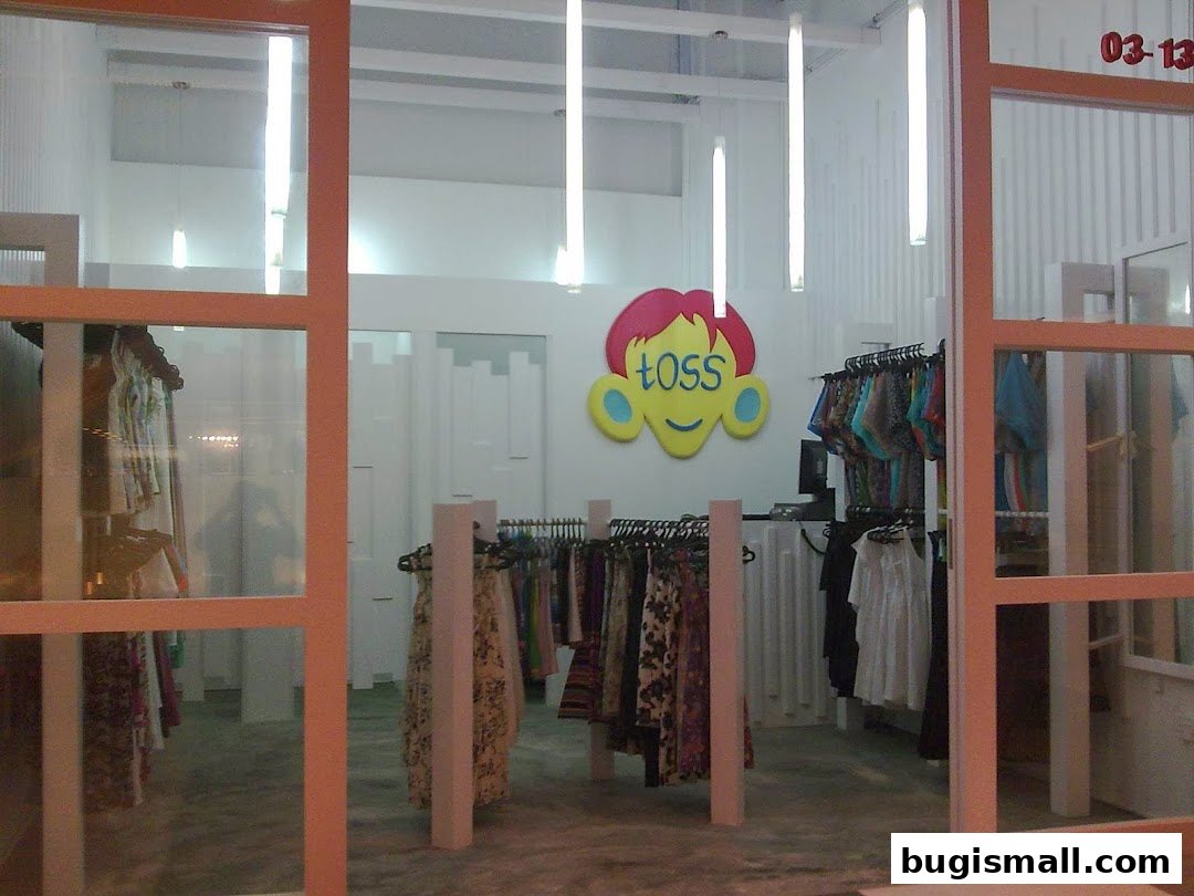 Interior view of a clothing store with racks of colorful apparel and the shop's logo.