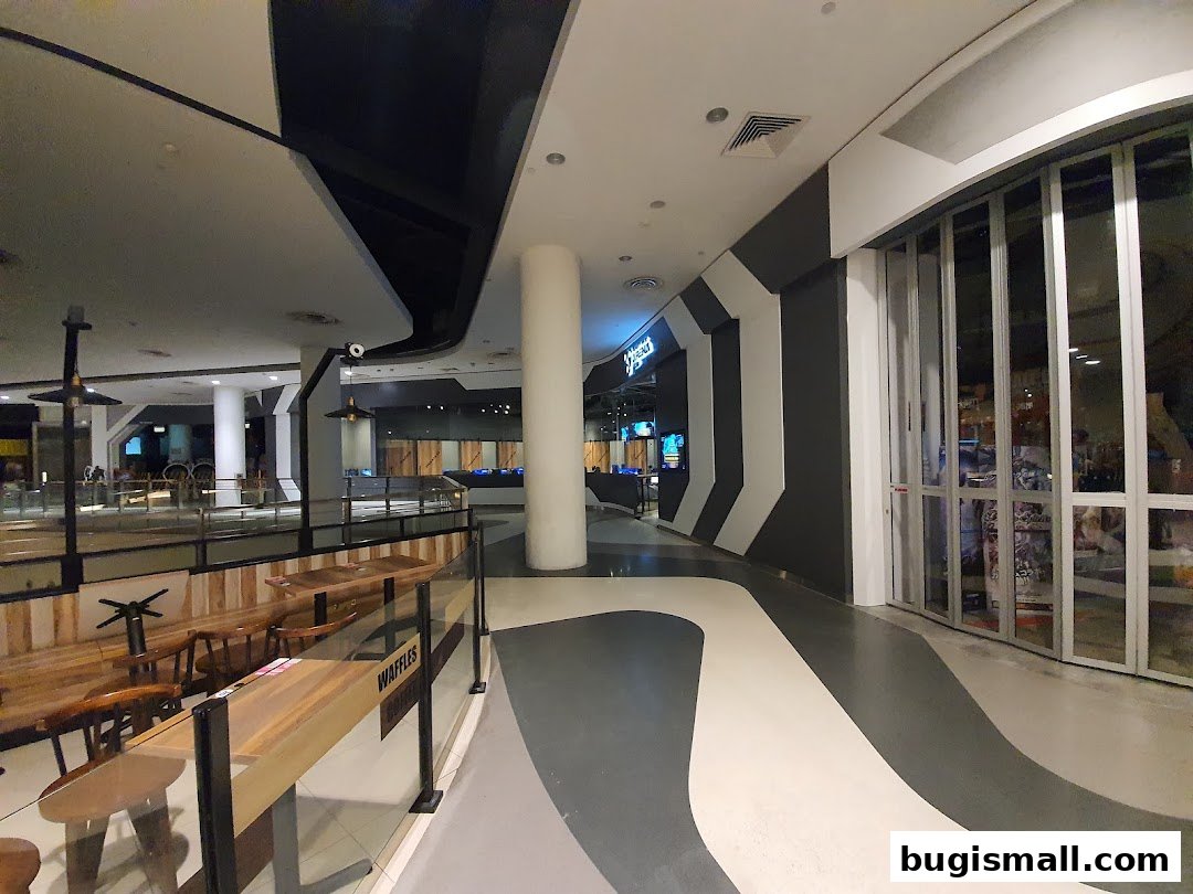 Interior view of a shopping mall with a shop entrance and seating area.