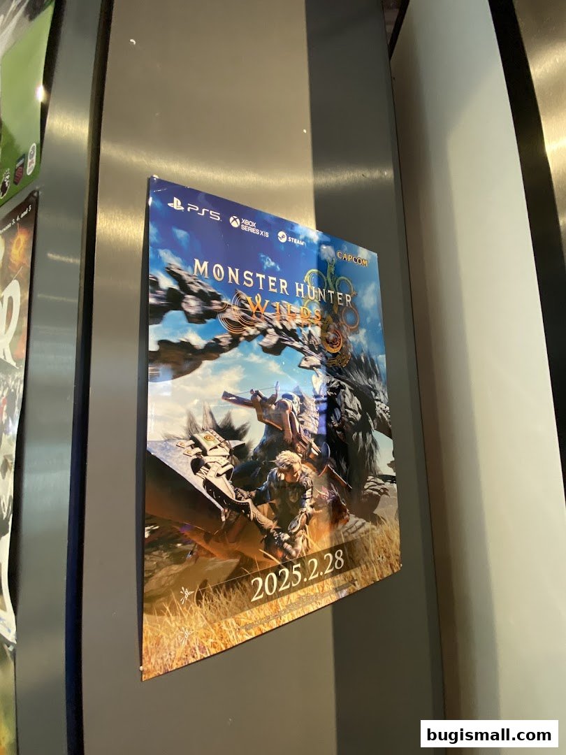 A poster for the game Monster Hunter Wilds is displayed on a metallic surface.