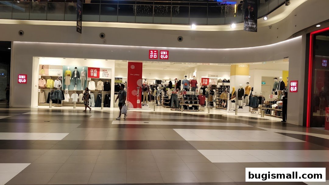The entrance of a UNIQLO store showcasing various clothing items on mannequins and racks.