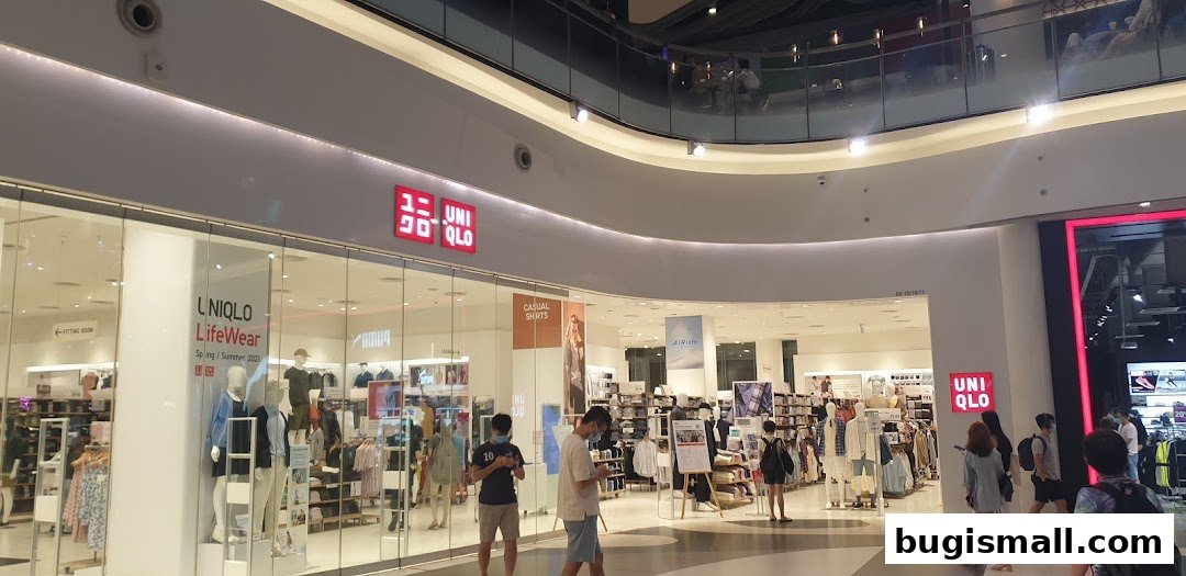 The exterior of a brightly lit Uniqlo store with mannequins and clothing displays visible.