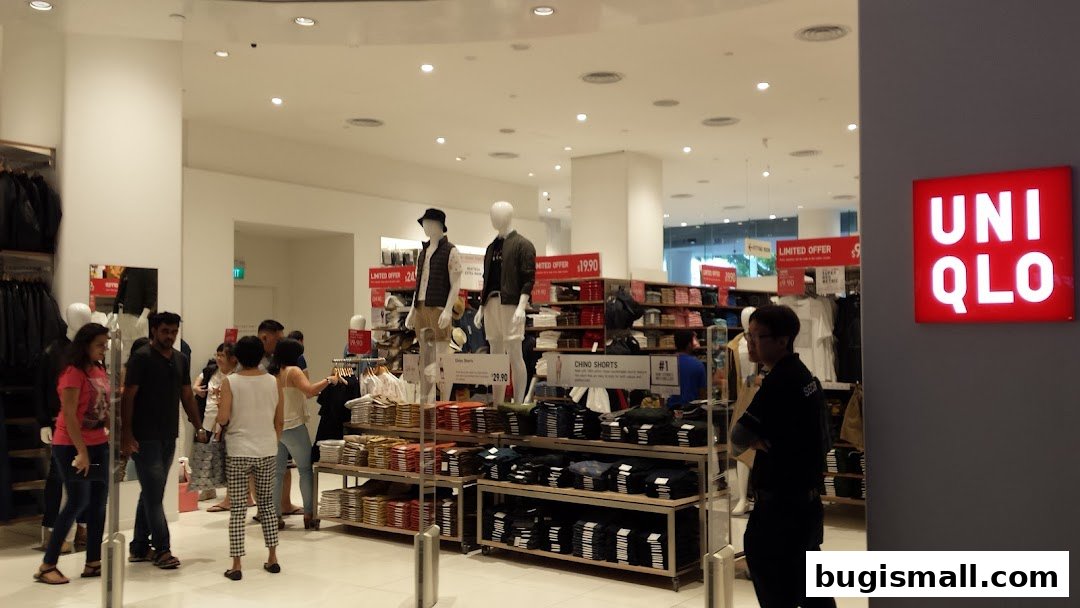Interior view of a UNIQLO store with mannequins, clothing displays, and shoppers.