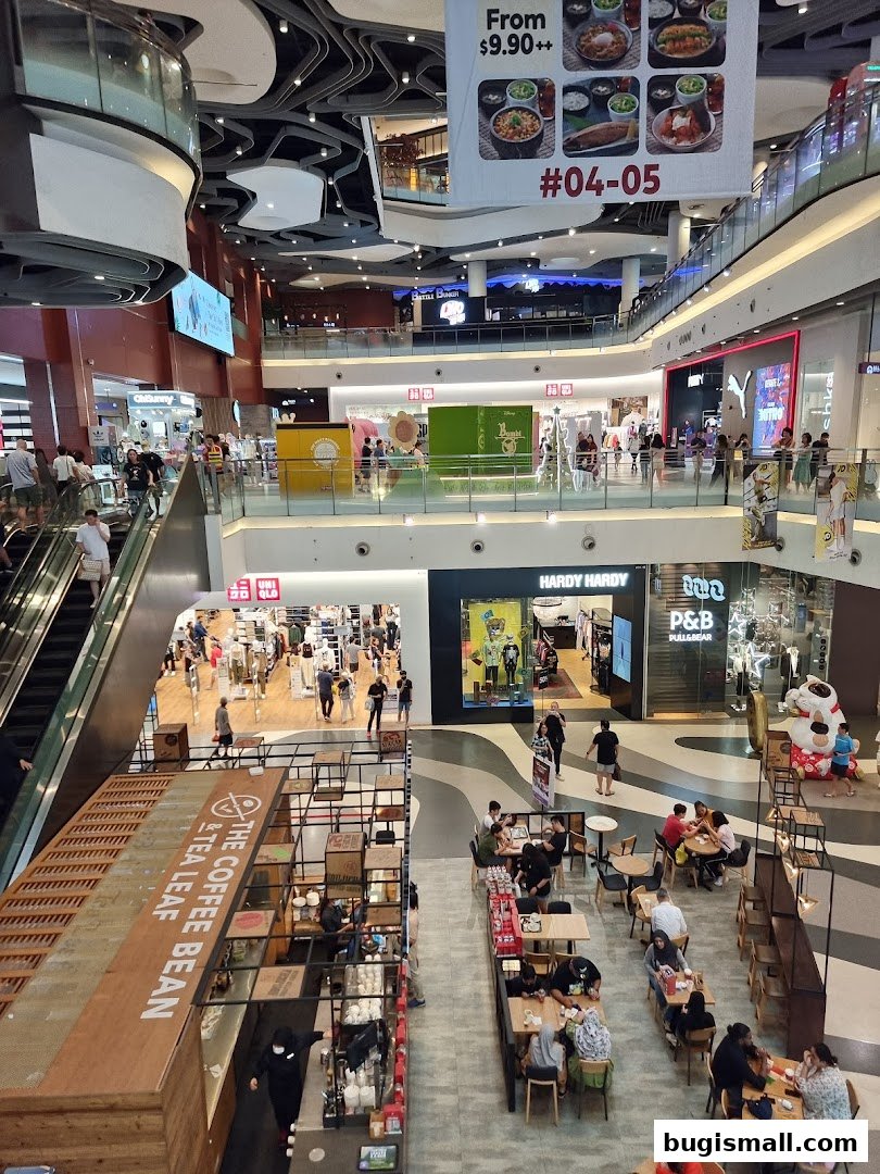 A busy shopping mall interior with various shops, escalators, and a coffee shop.
