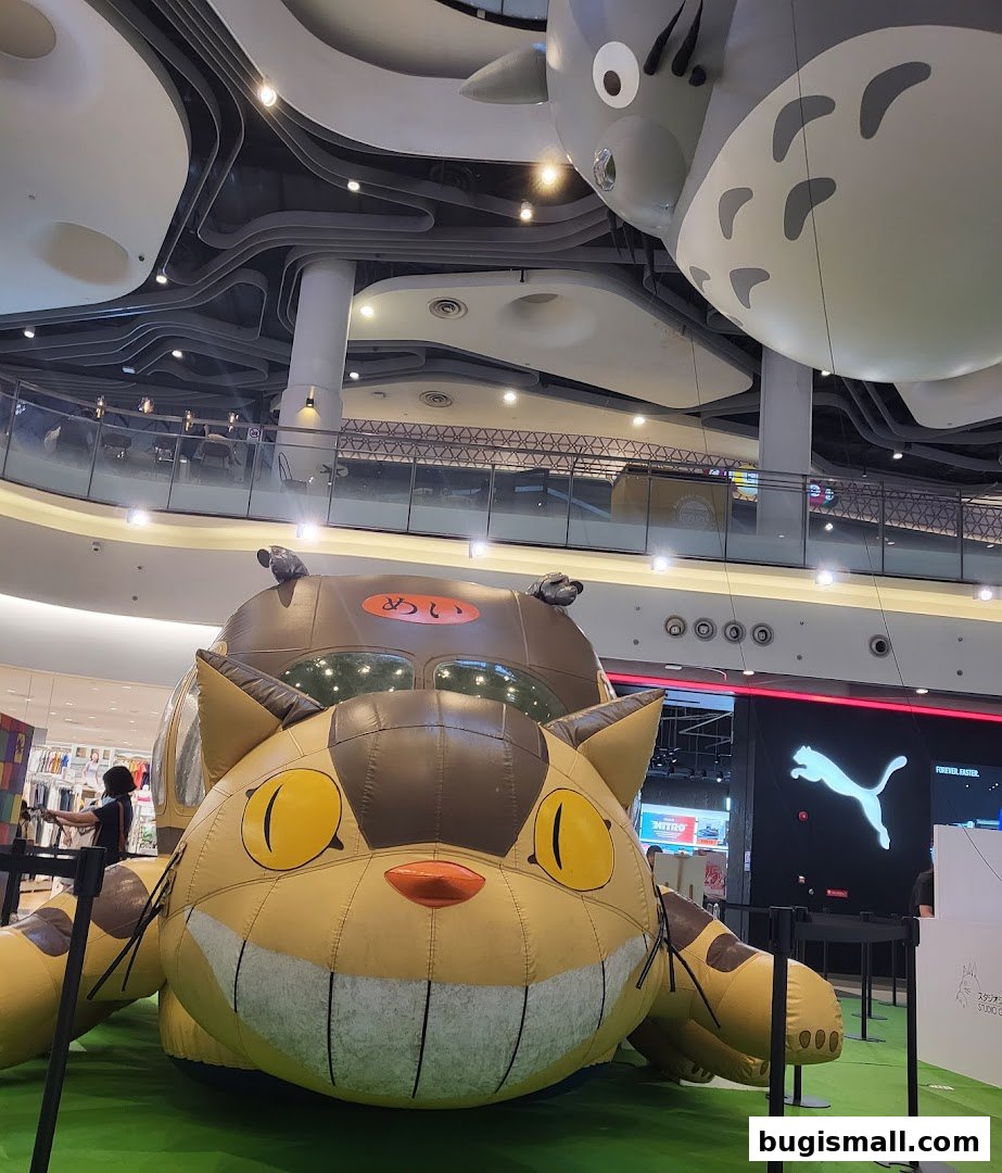 Giant inflatable Totoro characters displayed in a shopping mall with a Puma store in the background.