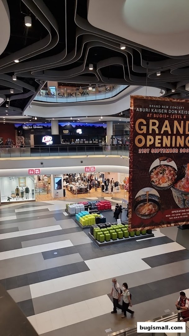 View of a shopping mall interior with Uniqlo store and a grand opening banner.