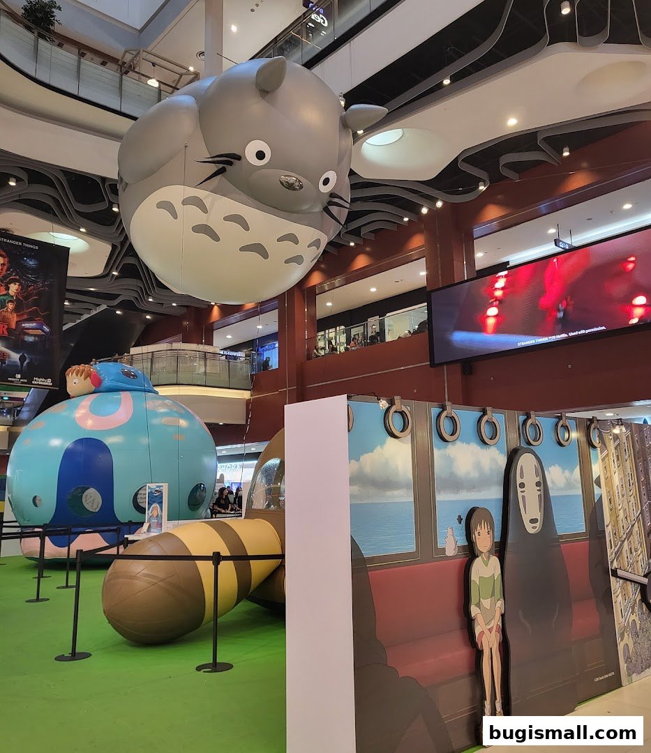 A large Totoro inflatable hangs above a Ghibli-themed display with characters from Spirited Away.