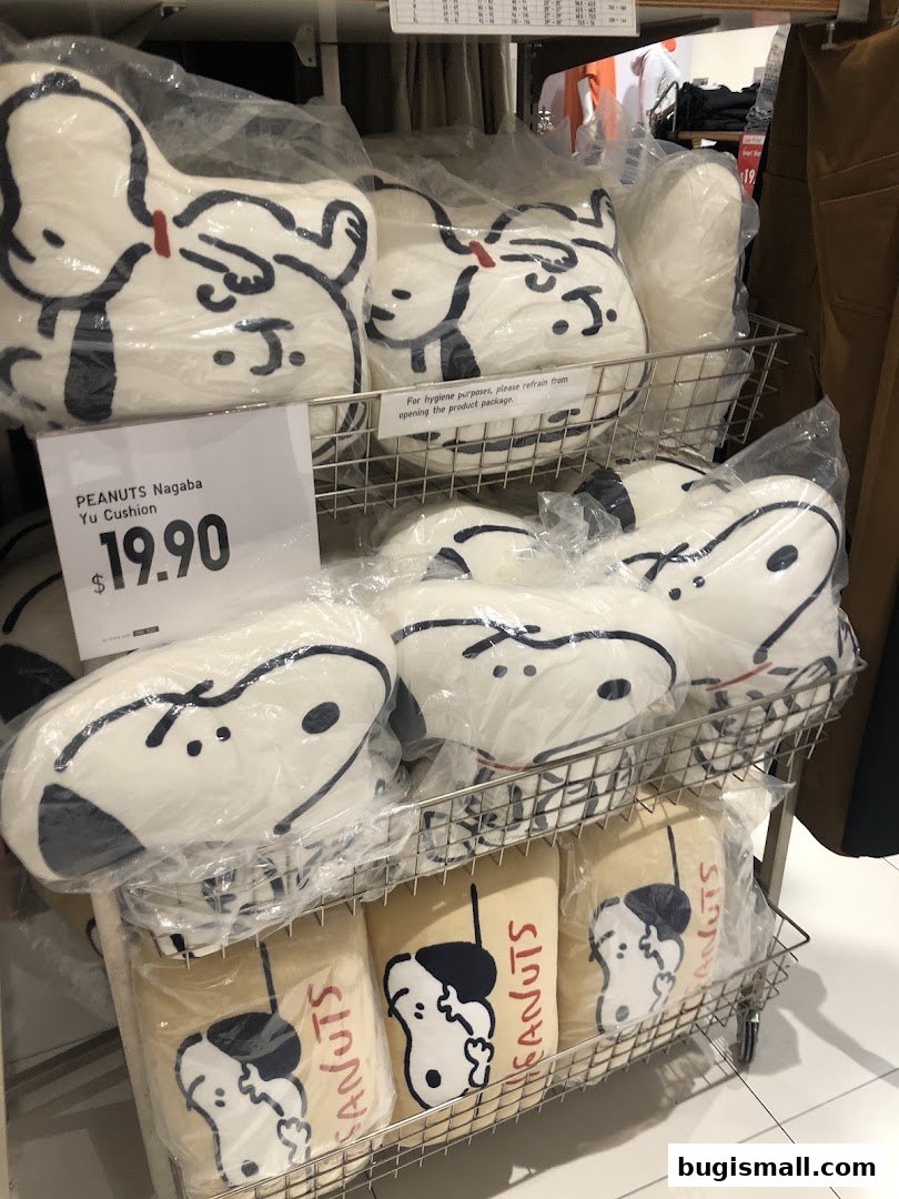 Shelves filled with PEANUTS themed cushions, some with price tags.