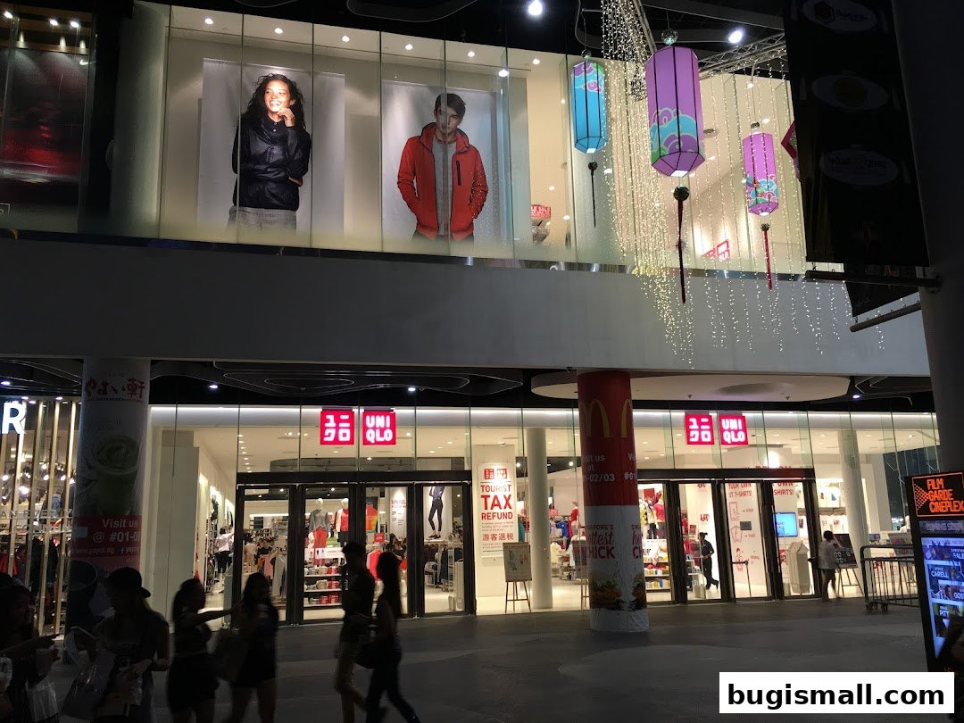 The brightly lit entrance of a UNIQLO store with mannequins and promotional displays.