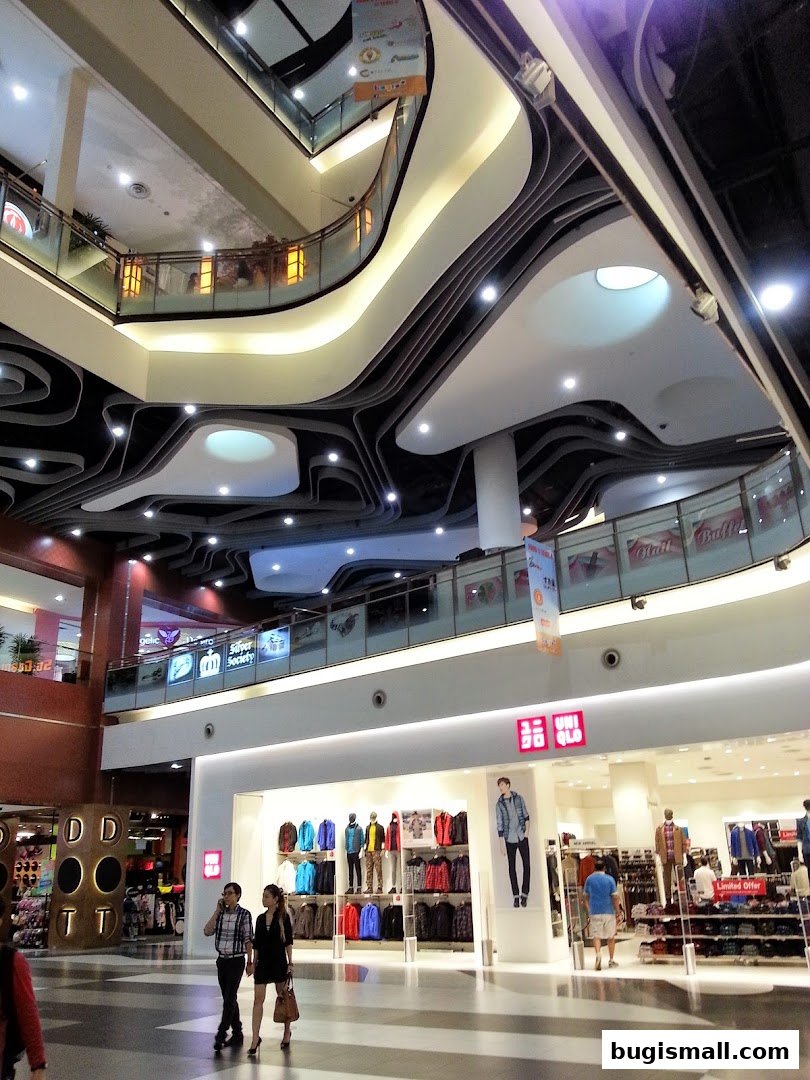UNIQLO store entrance with mannequins displaying clothing and shoppers walking by.