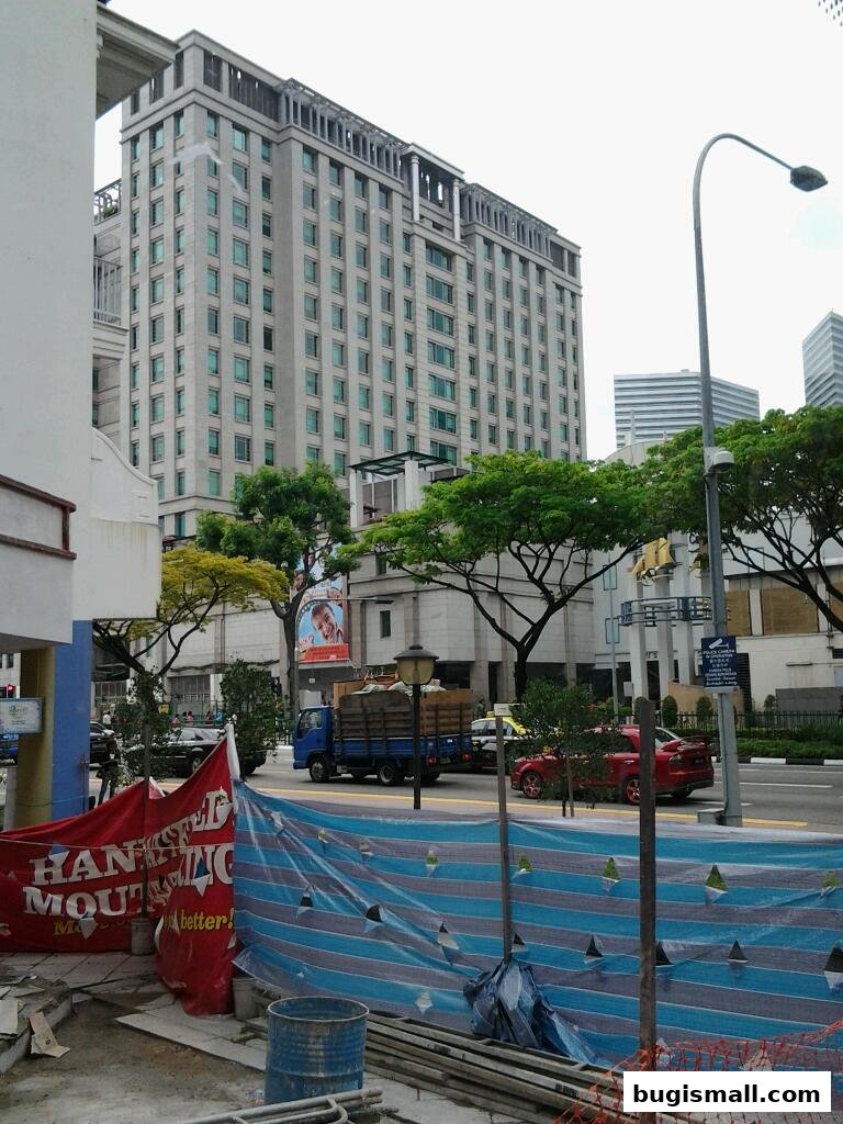 A street view with a large building, construction barriers, and a truck.