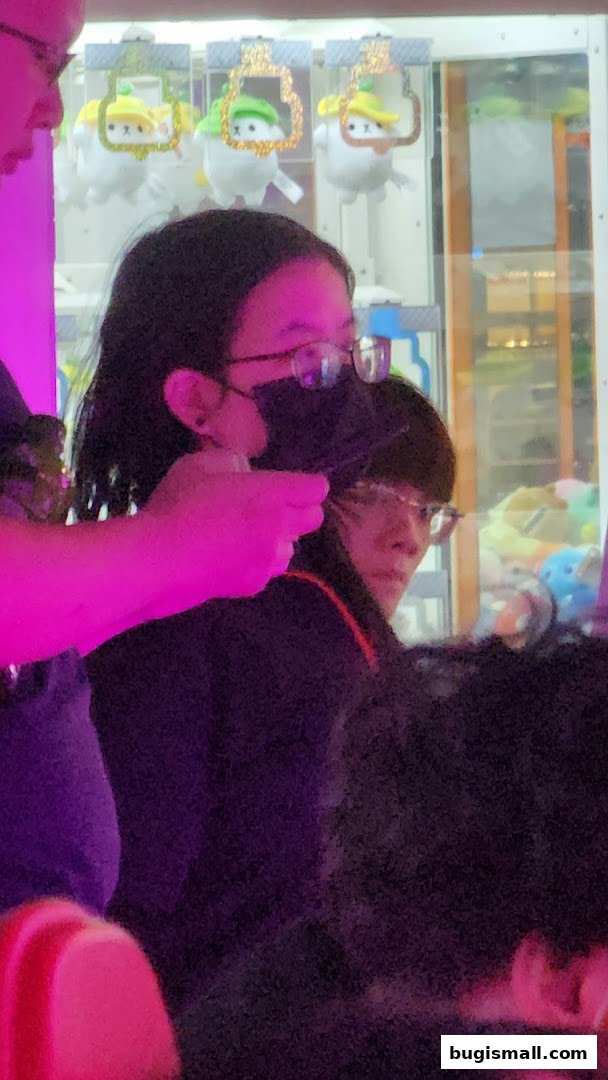 People playing a claw machine with plush toys inside.