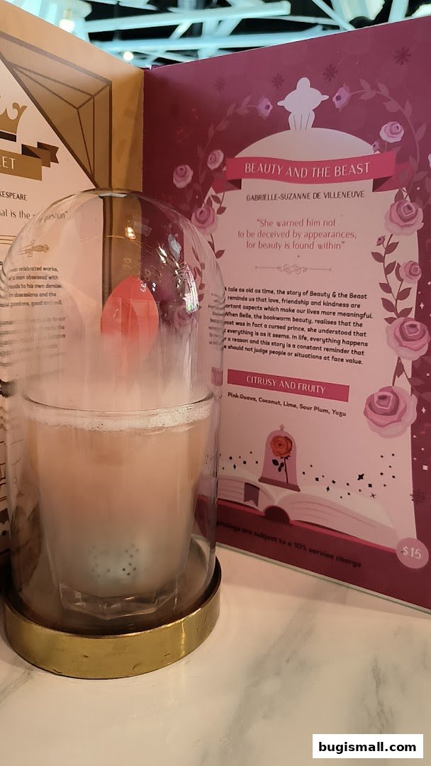 A cocktail served under a glass dome next to a menu themed around Beauty and the Beast.