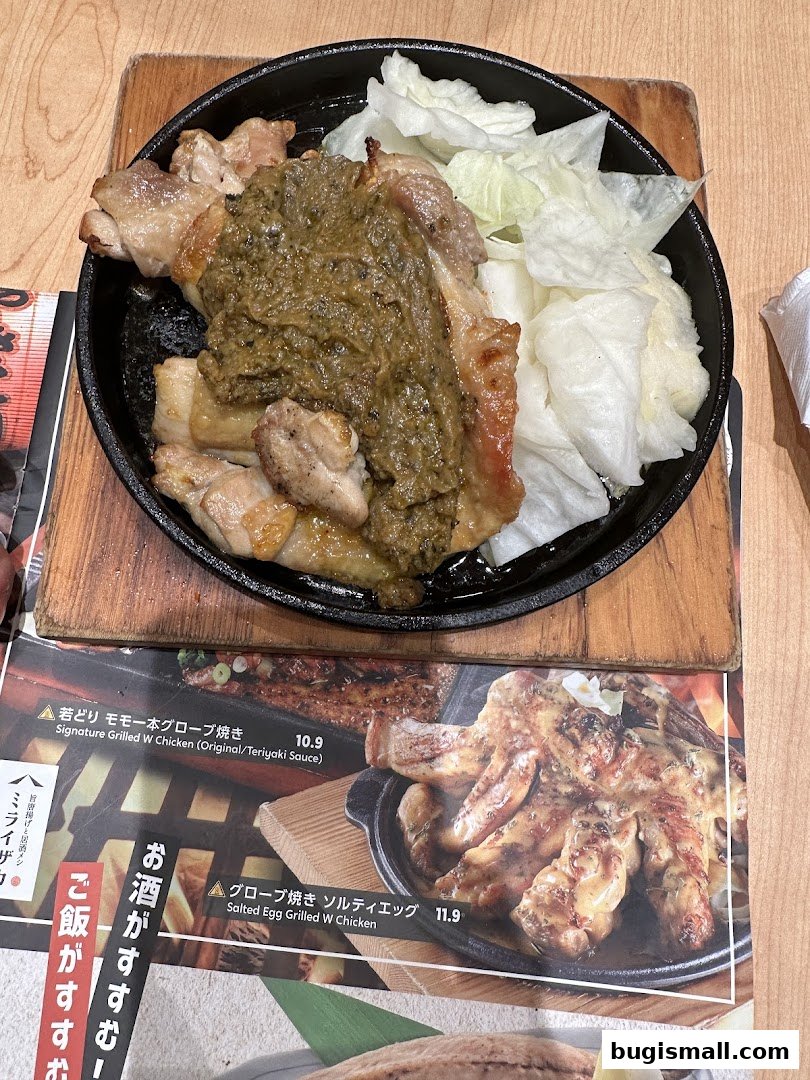 A close-up of a sizzling plate of grilled chicken with a side of lettuce, served with a menu.