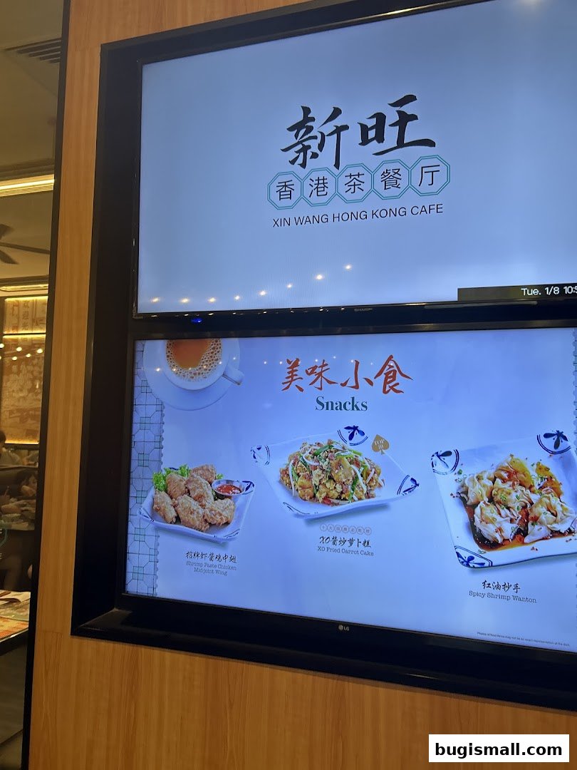 A digital menu board displaying the Xin Wang Hong Kong Cafe logo and various snack items.