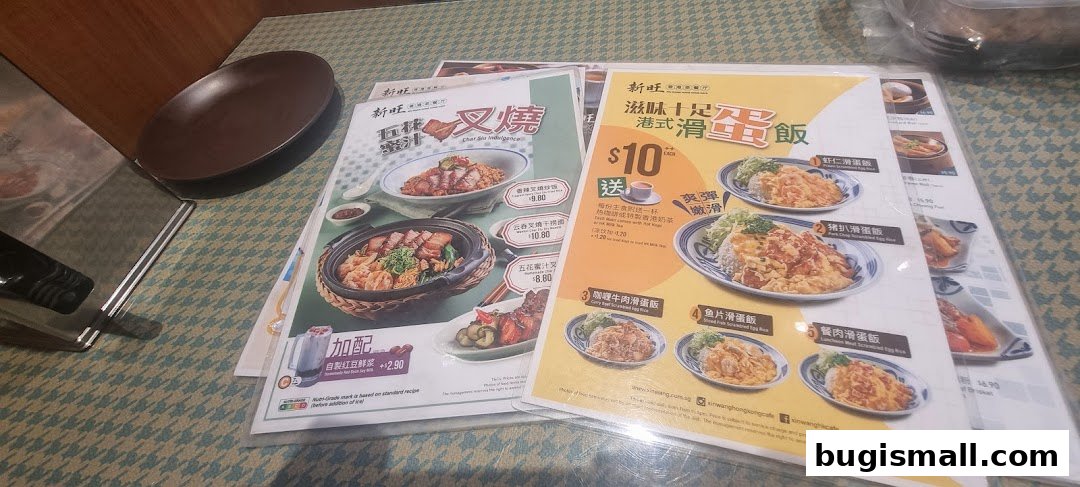 A close-up view of menus from Xin Wang Hong Kong Cafe, showcasing various dishes.