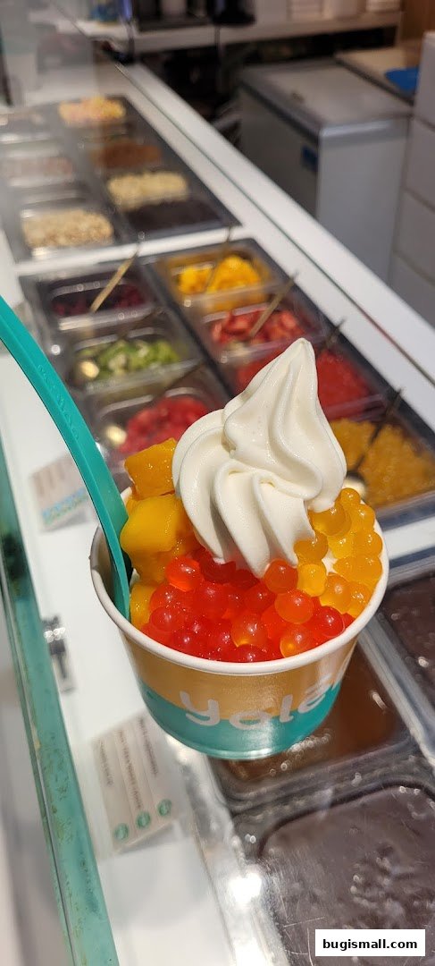 A cup of frozen yogurt topped with mango chunks and popping boba pearls.